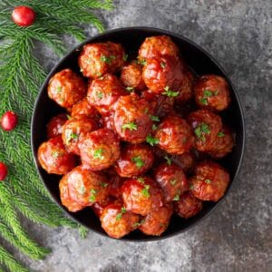 Crock pot cranberry meatballs in a black bowl garnished with parsley.