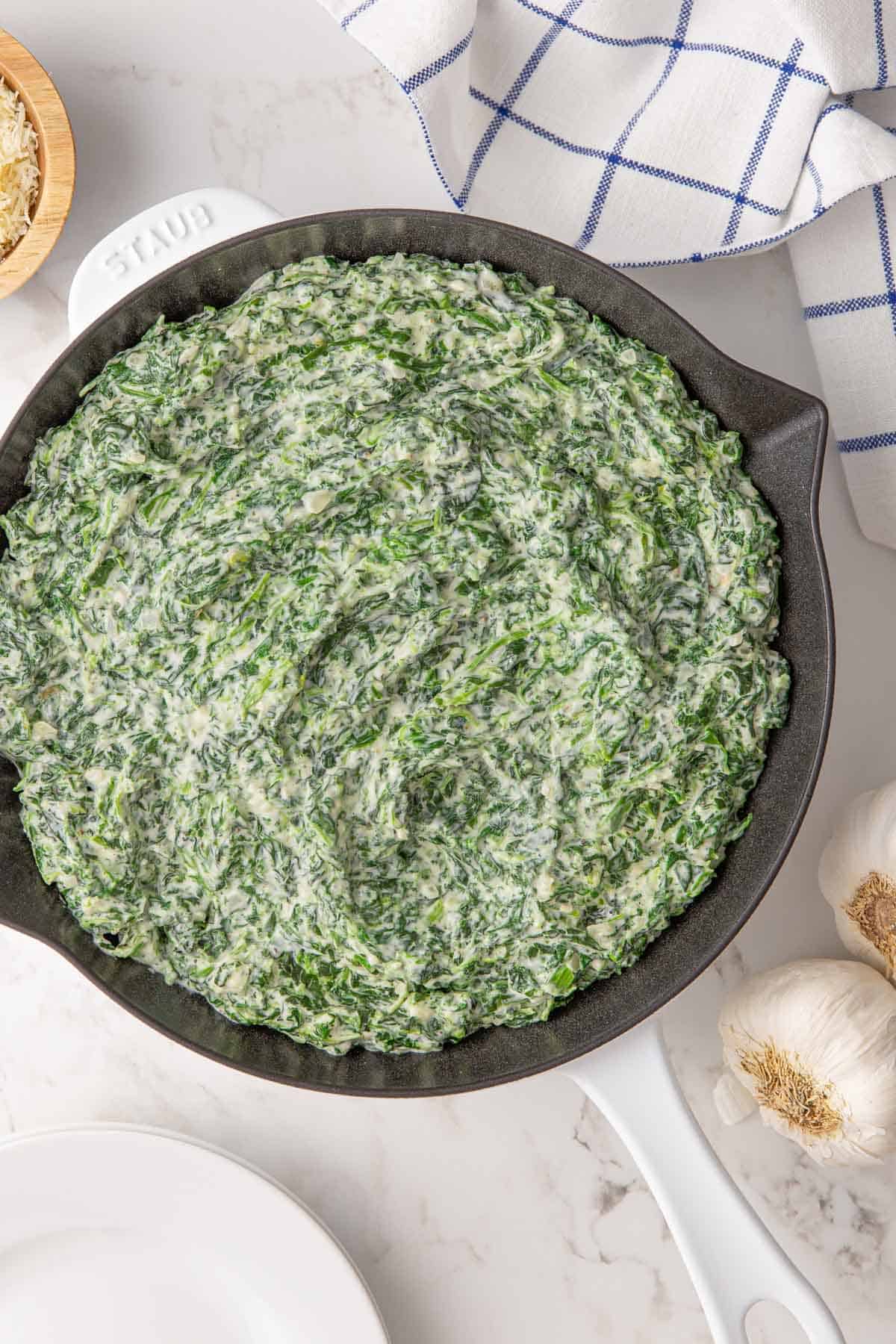 Overhead view of creamed spinach in a white skillet.