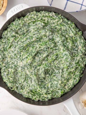 Overhead view of easy creamed spinach in a white skillet.