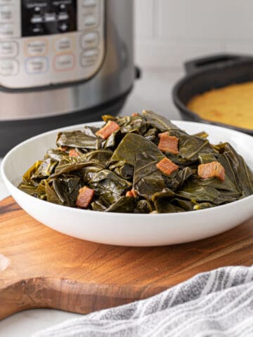 A white bowl of collard greens with an Instant Pot in the background.