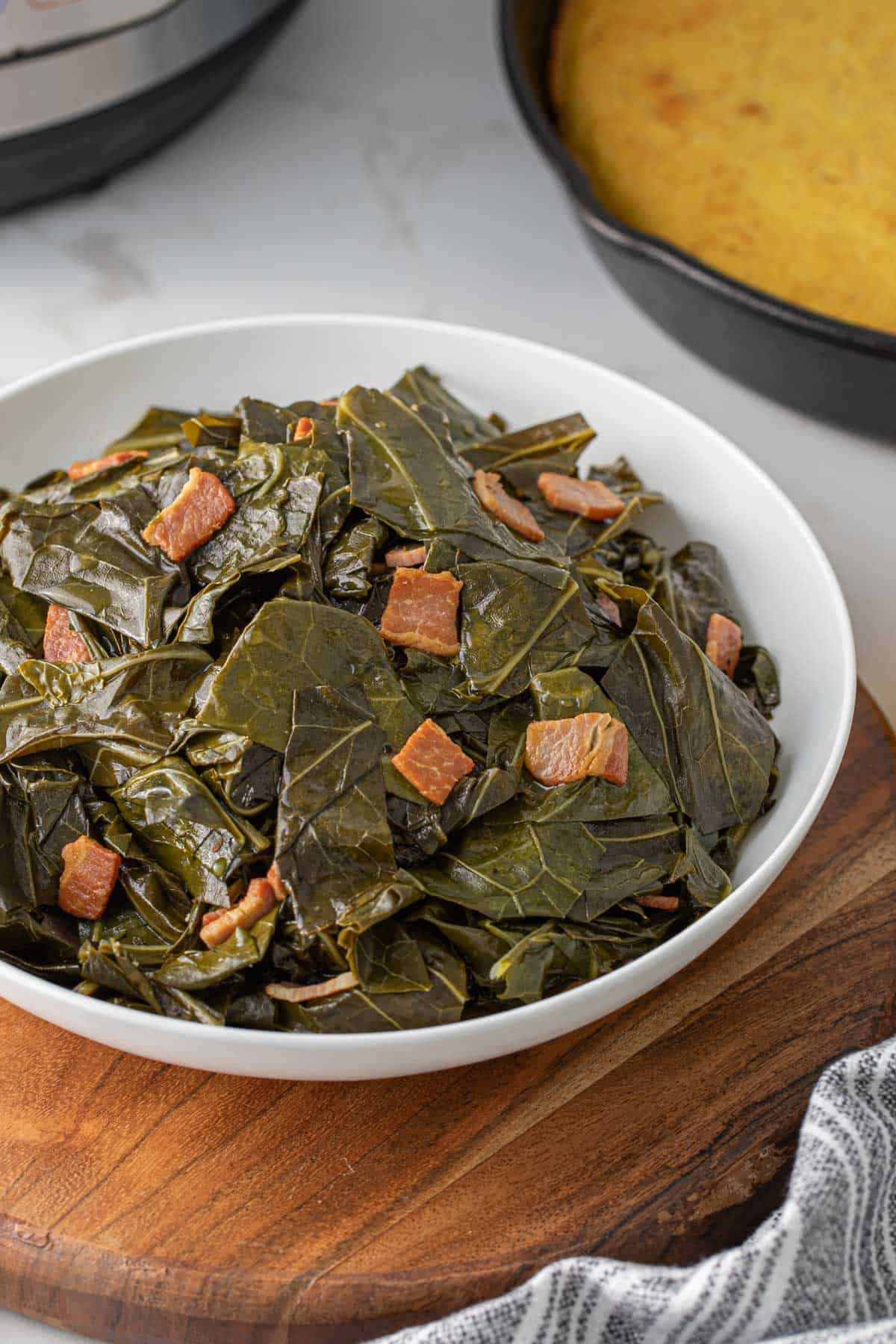 A closeup view of a white bowl of pressure cooker collard greens.