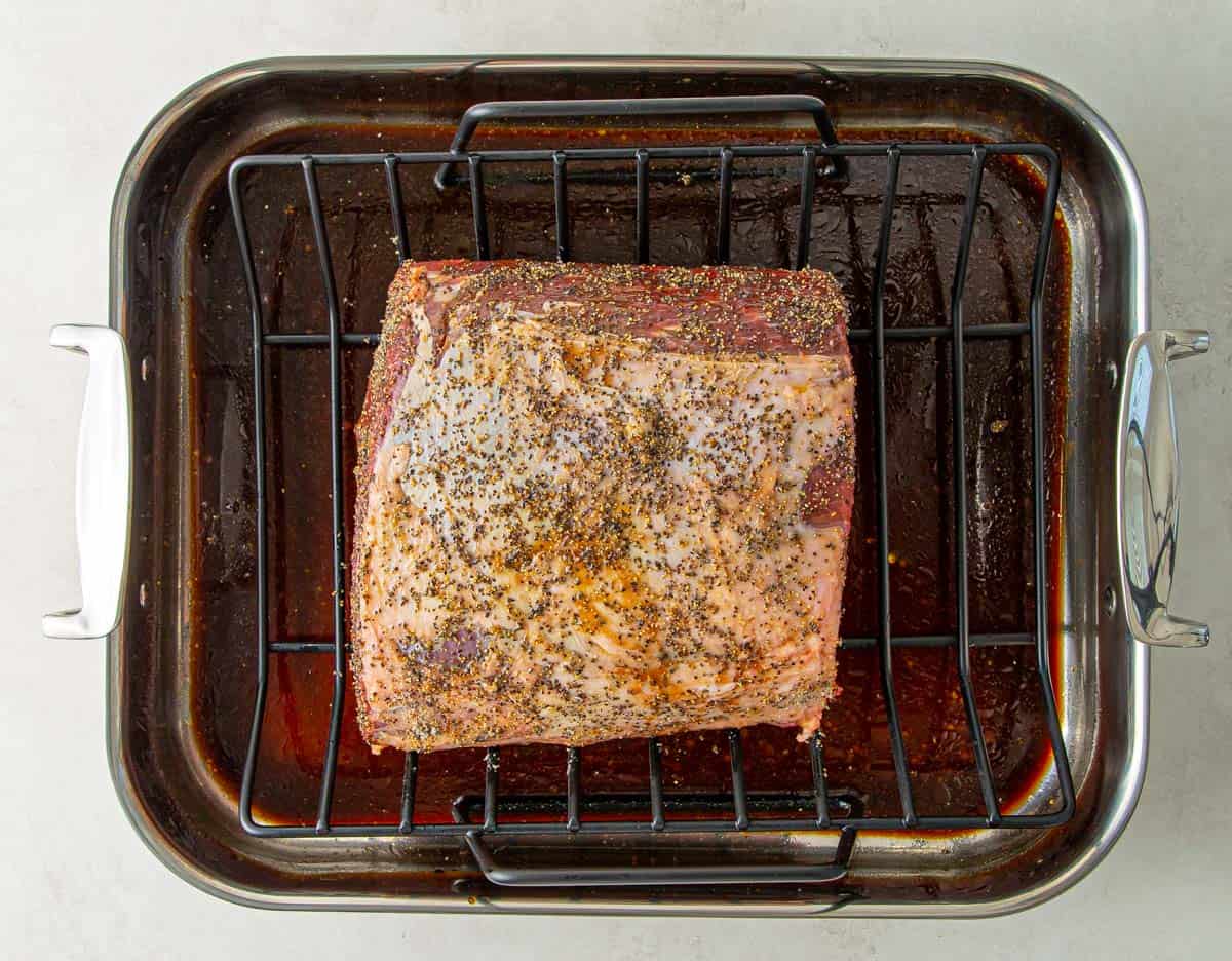 An uncooked boneless prime rib  rubbed with olive oil, salt and pepper in a roasting pan.