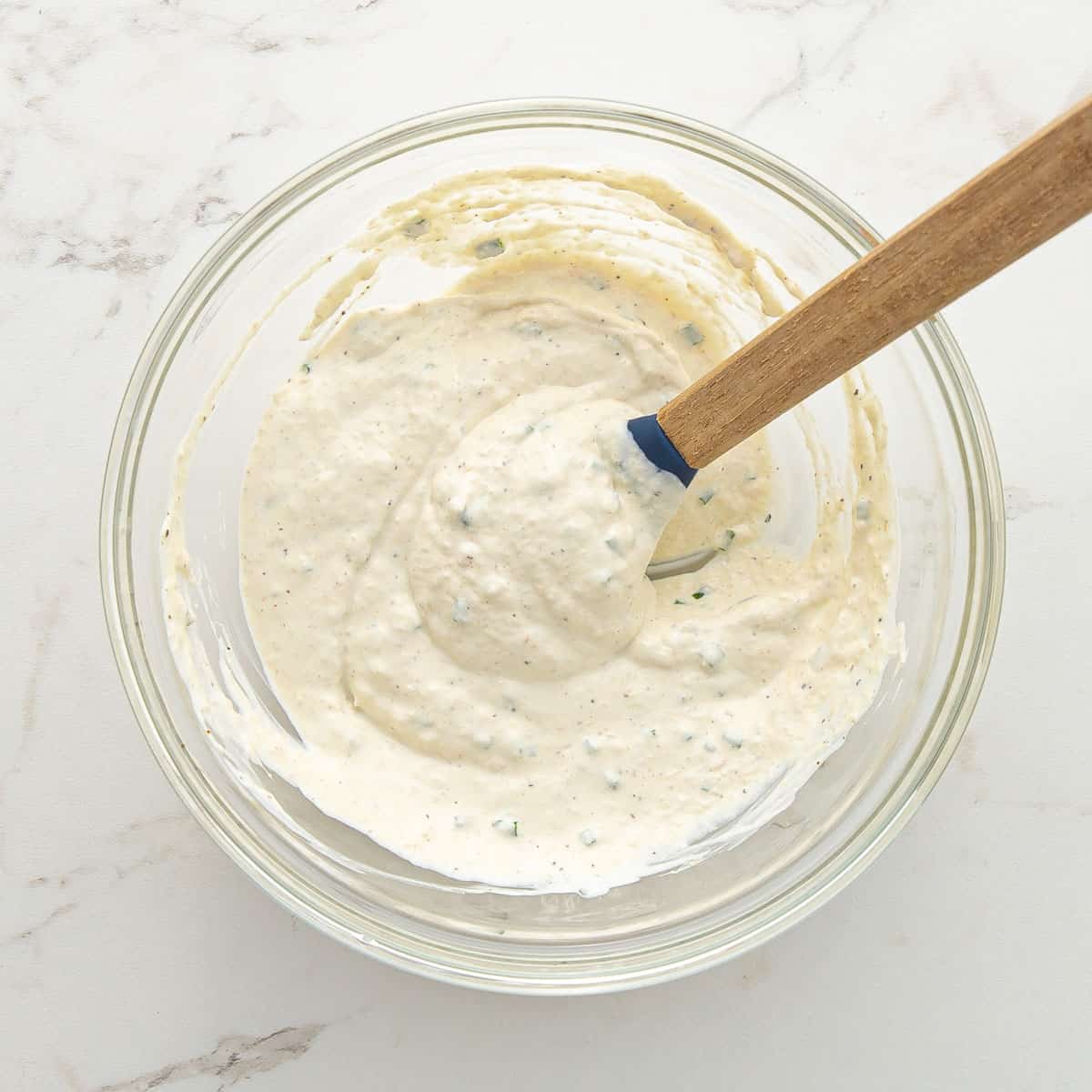 Horseradish sauce in a small mixing bowl with a wooden spoon.