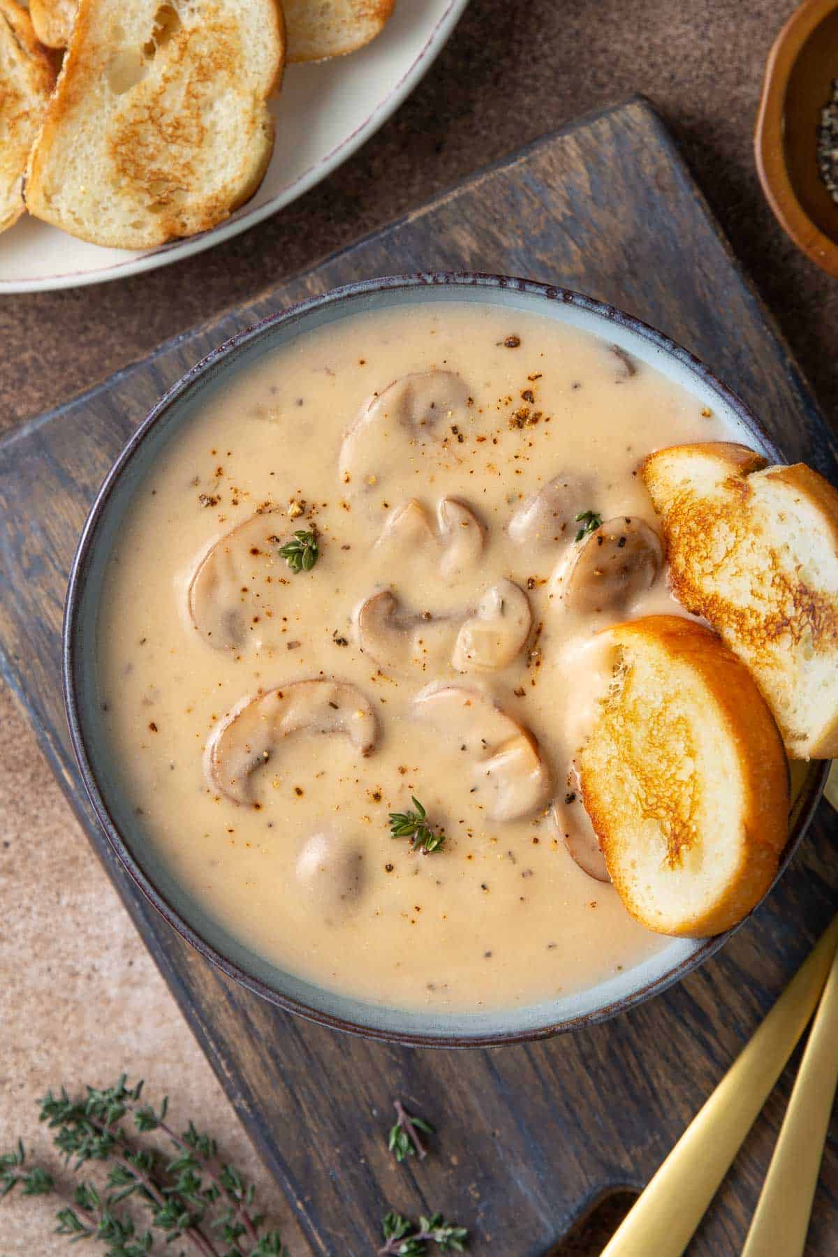Overhead view of cream of mushroom soup in a blue bowl with French bread.