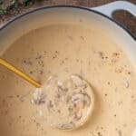 Cream of mushroom soup in a white Dutch oven with a ladle. Overlay text at top of image.