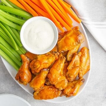 Crock Pot Buffalo Wings on a serving platter with vegetables and a bowl of ranch dressing.
