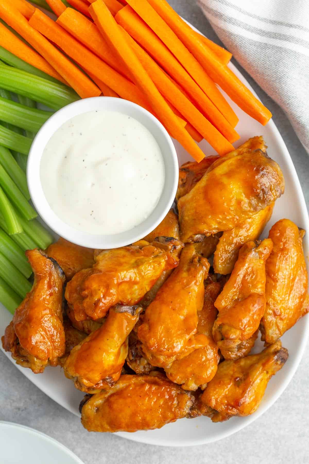Overhead closeup view of buffalo wings on a platter with vegetables and ranch dressing.