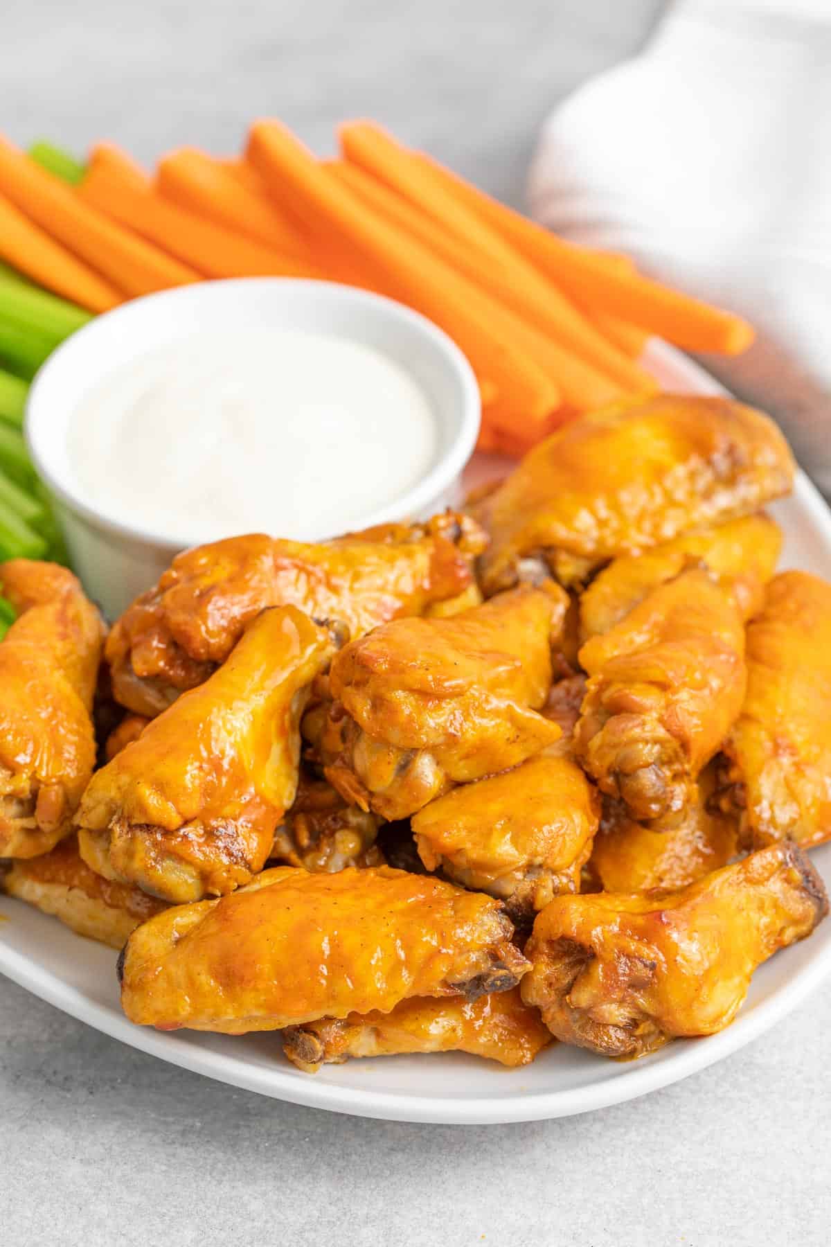 Front closeup view of slow cooker buffalo wings on an oval white platter.