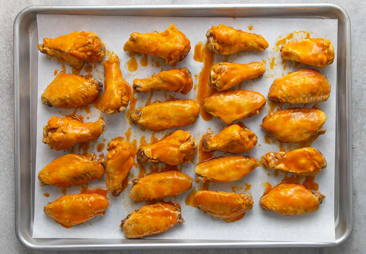 Buffalo wings on a baking sheet lined with parchment paper.