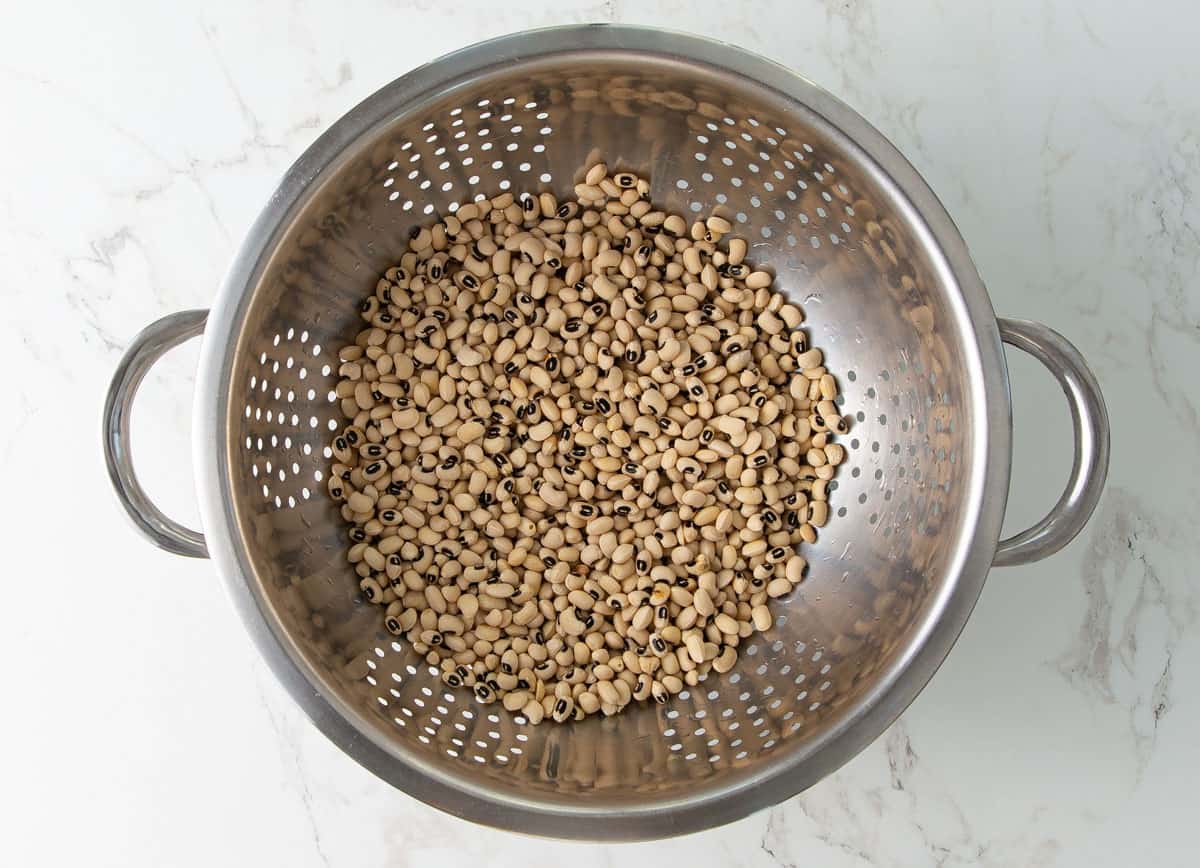Dry black-eyed peas that have been sorted and rinsed in a colander.