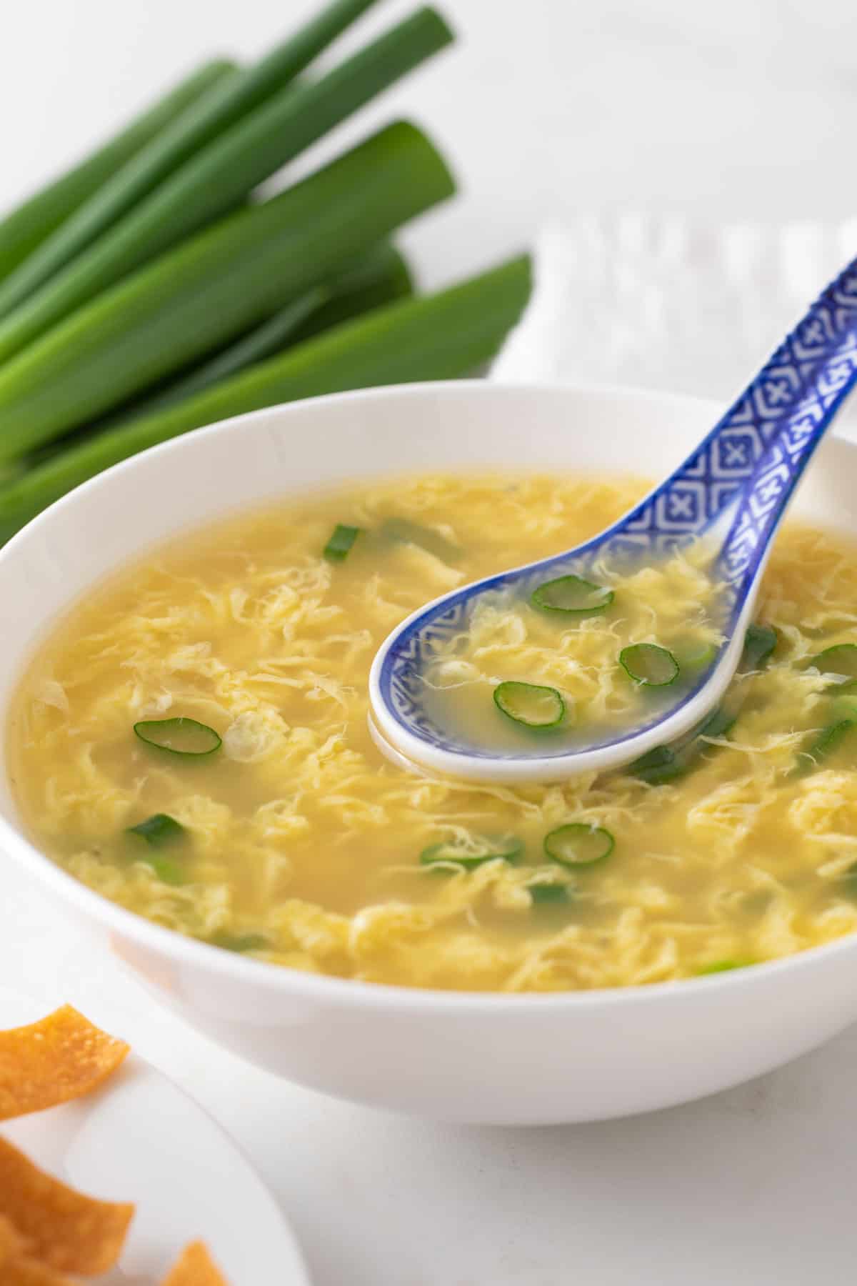 A blue and white Chinese soup spoon in a bowl of egg drop soup.