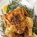 Air fryer whole chicken on a platter with fresh herbs. Overlay text at top of image.