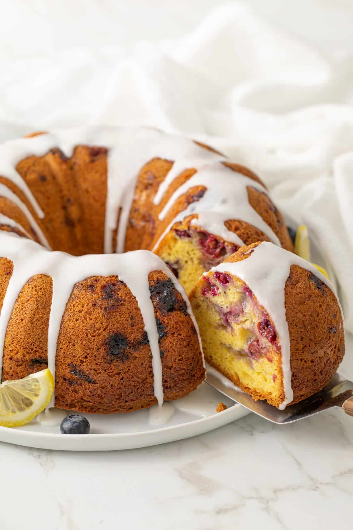 A slice of blueberry lemon Bundt cake being removed with a spatula.