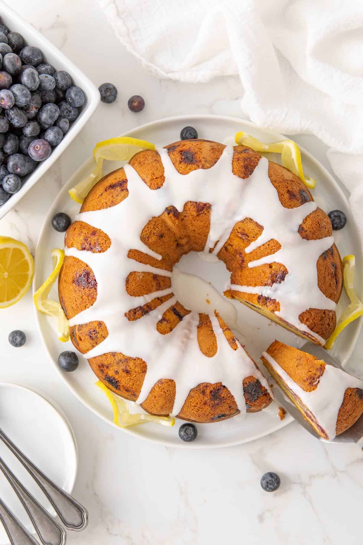 Overhead view of a blueberry lemon Bundt cake on a white cake platter.