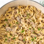 Ground beef stroganoff in a white Dutch oven. Overlay text at top of image.