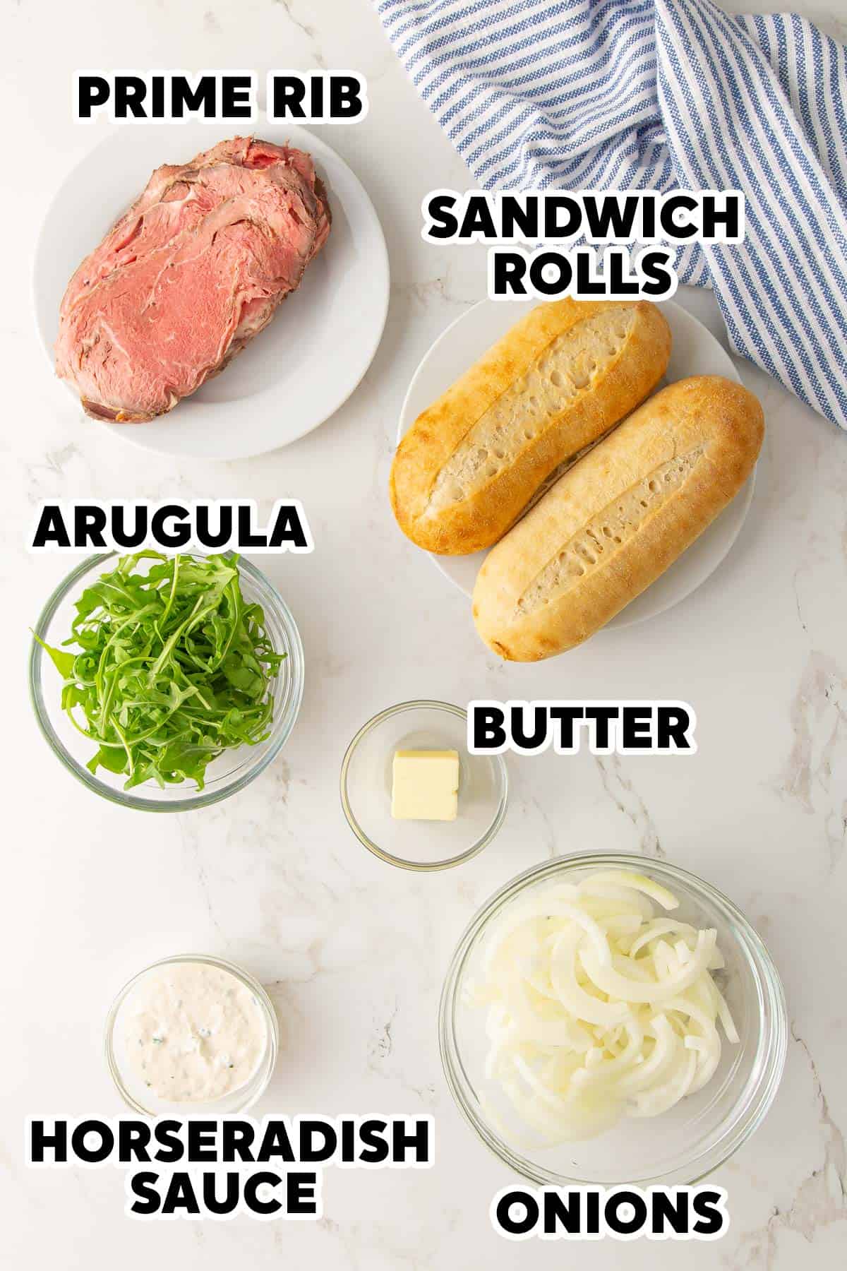 Ingredients for making prime rib sandwiches on white marble surface.