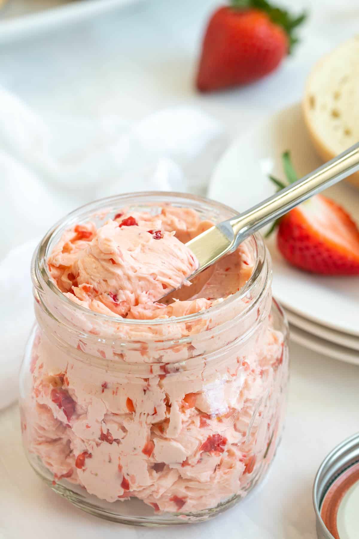 Strawberry honey butter in a mason jar with a spreading knife in the jar.