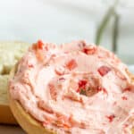 A closeup of a bagel spread with strawberry honey butter. Overlay text at top of image.