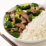 A closeup view of beef and broccoli in a bowl with white rice.