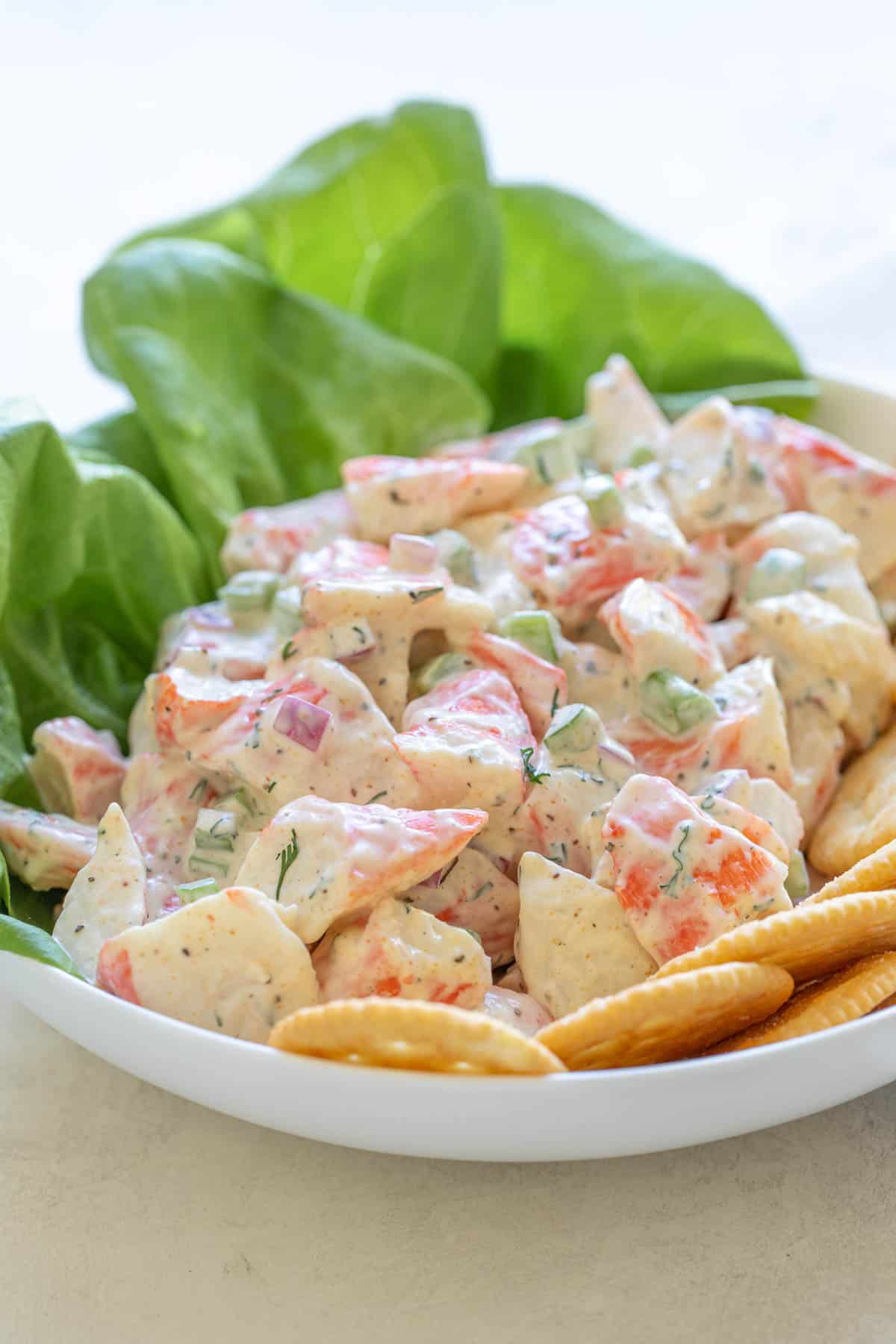 Front closeup view of imitation crab salad in a bowl with lettuce and crackers.