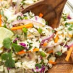 Closeup view of Mexican coleslaw in a bowl with salad servers. Overlay text at top of image.