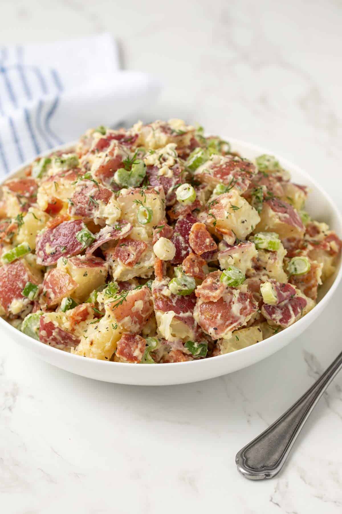 Front view of red potato salad in a white bowl.
