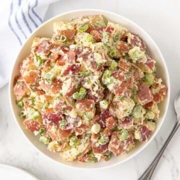 Overhead view of red potato salad in a white serving bowl.