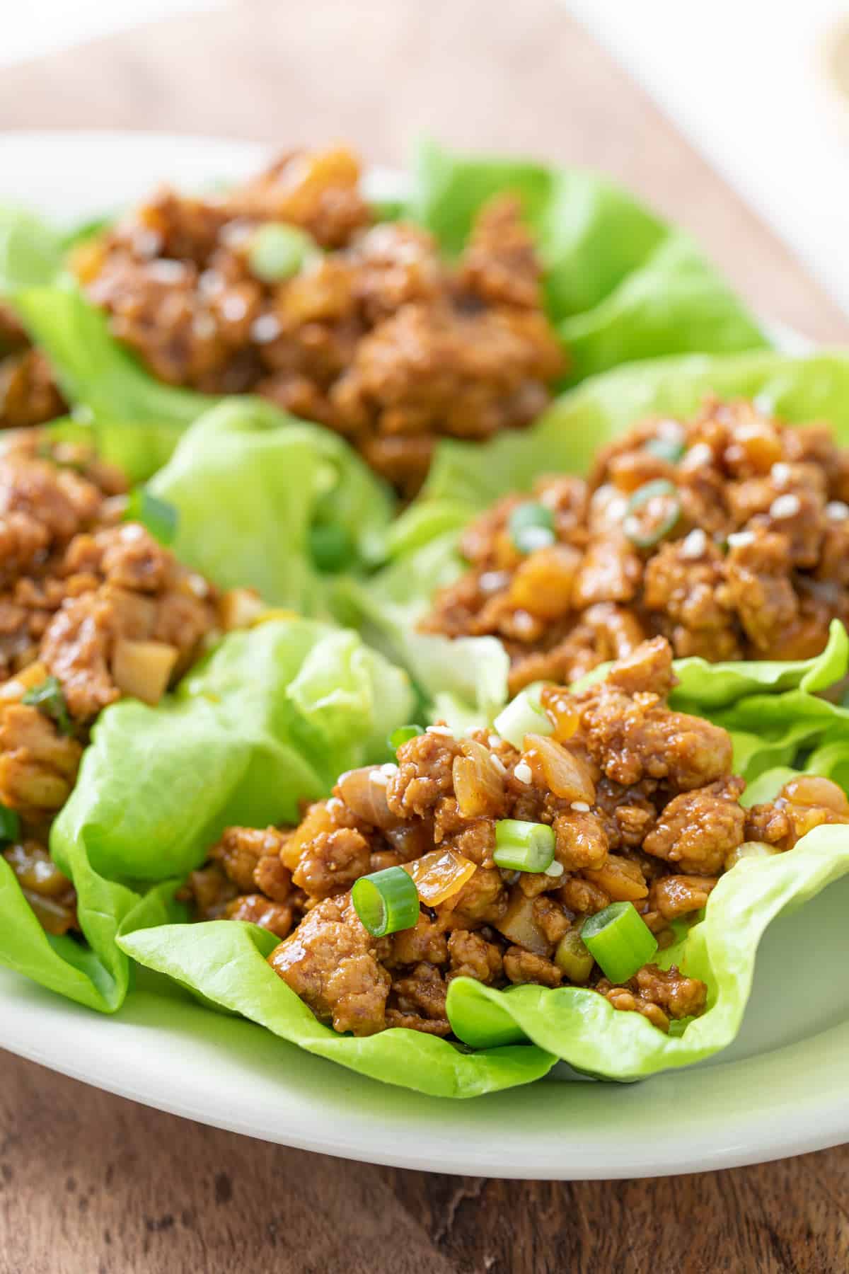 Asian chicken lettuce wraps on an oval white plate.
