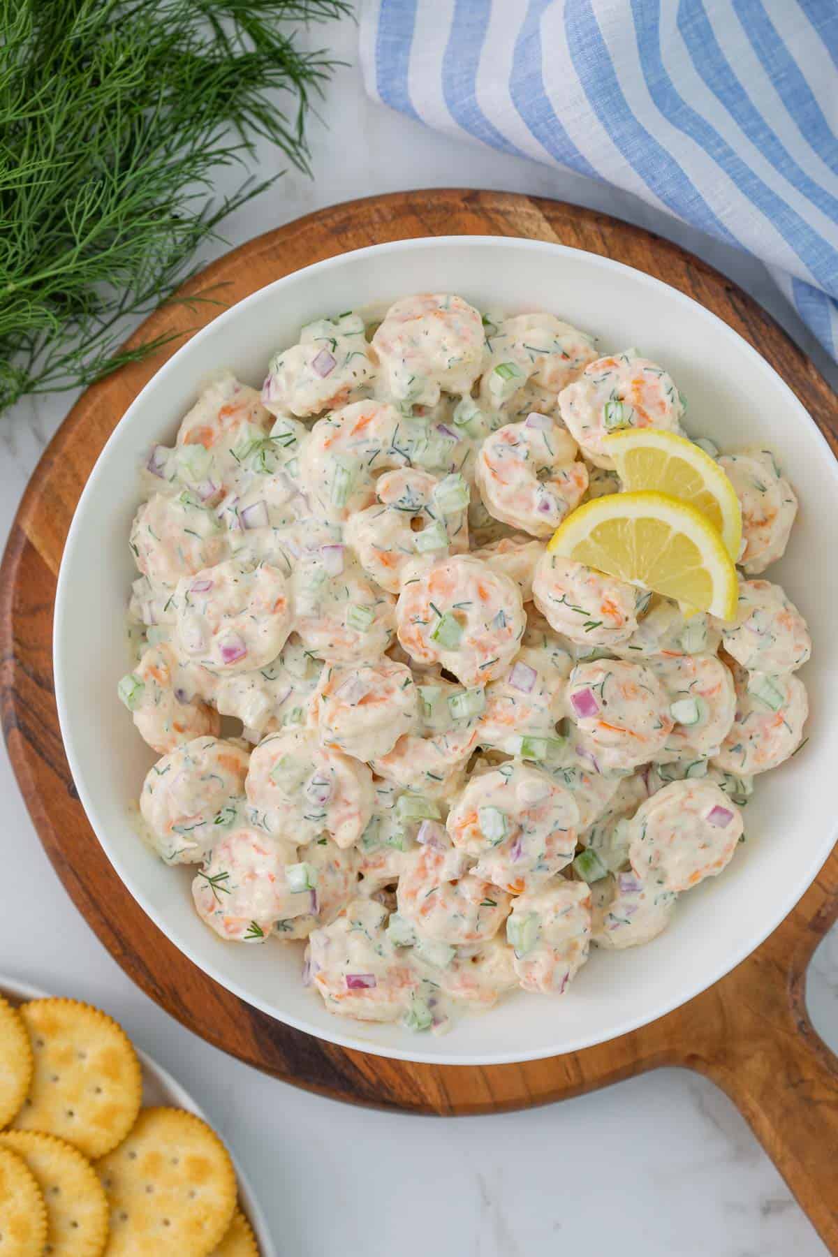 Shrimp salad in a white bowl beside a plate of crackers.
