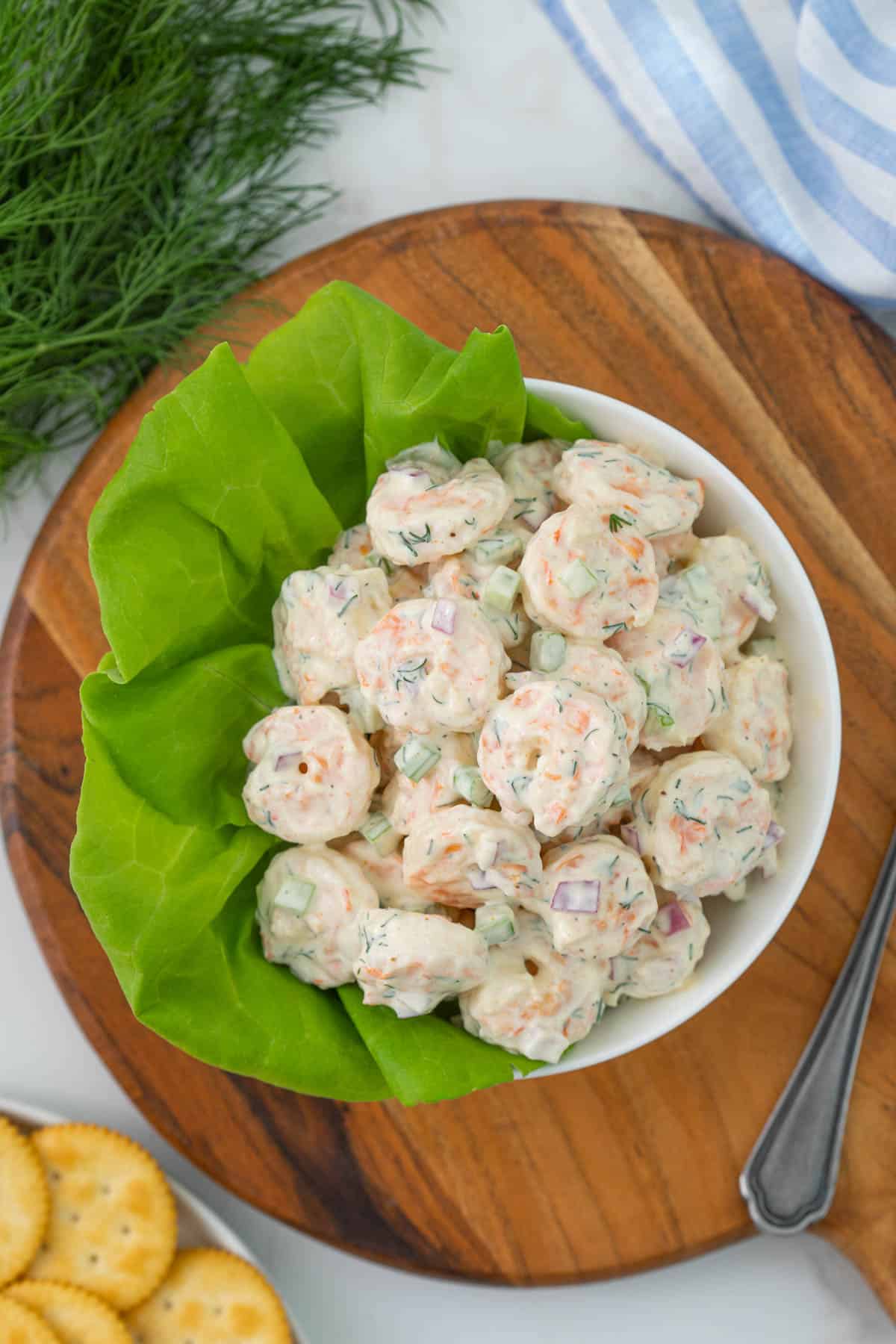 Overhead view of shrimp salad in a white bowl with lettuce.