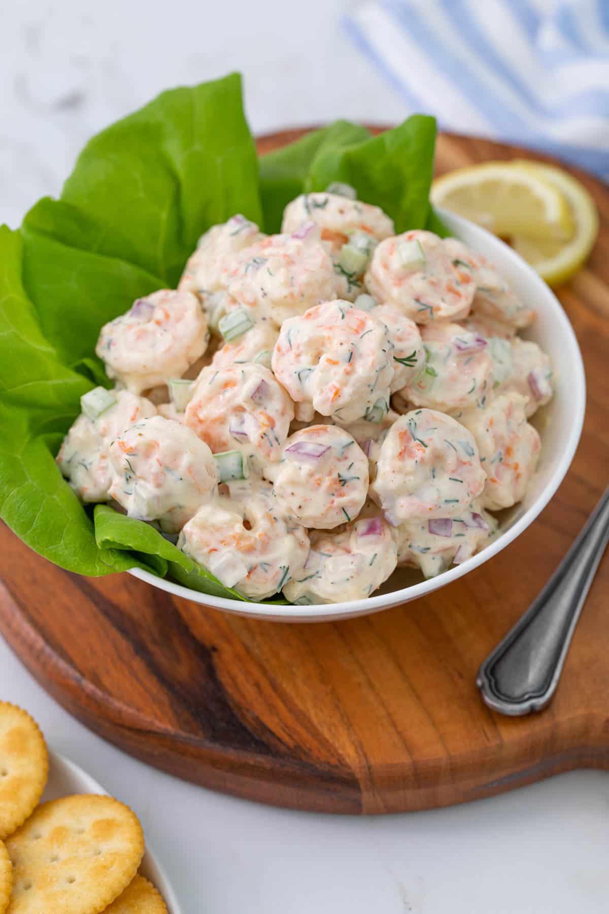 A white bowl of shrimp salad with lettuce.
