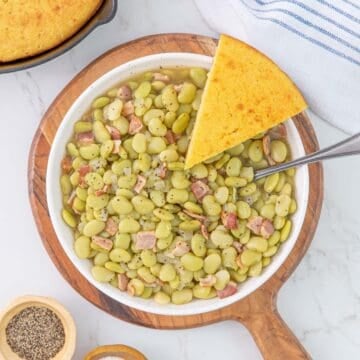 Overhead view of a bowl of southern butter beans with a slice of cornbread.