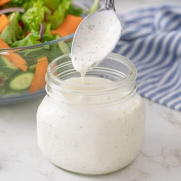 A spoon is being removed from a jar of homemade buttermilk ranch dressing.