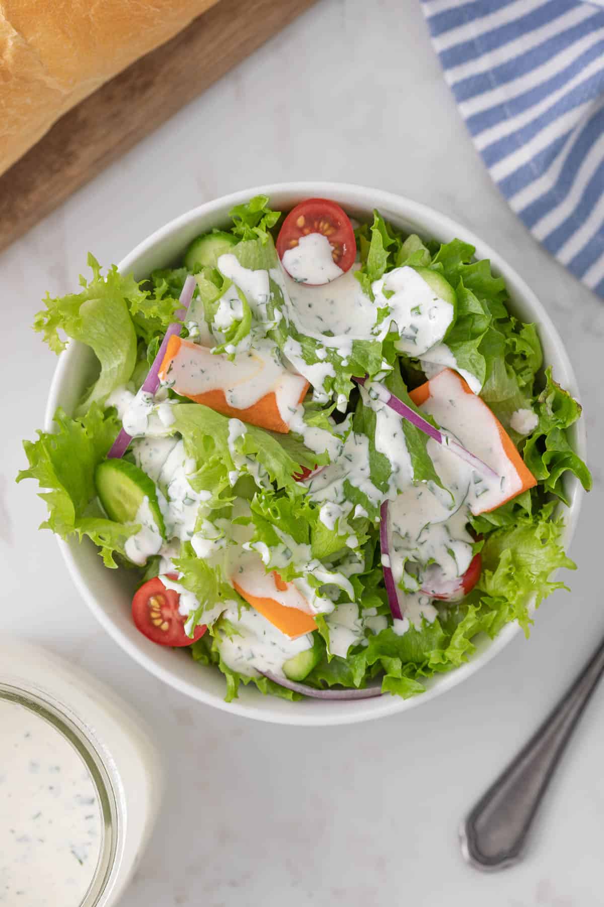 Overhead view of a garden salad drizzled with buttermilk ranch dressing.
