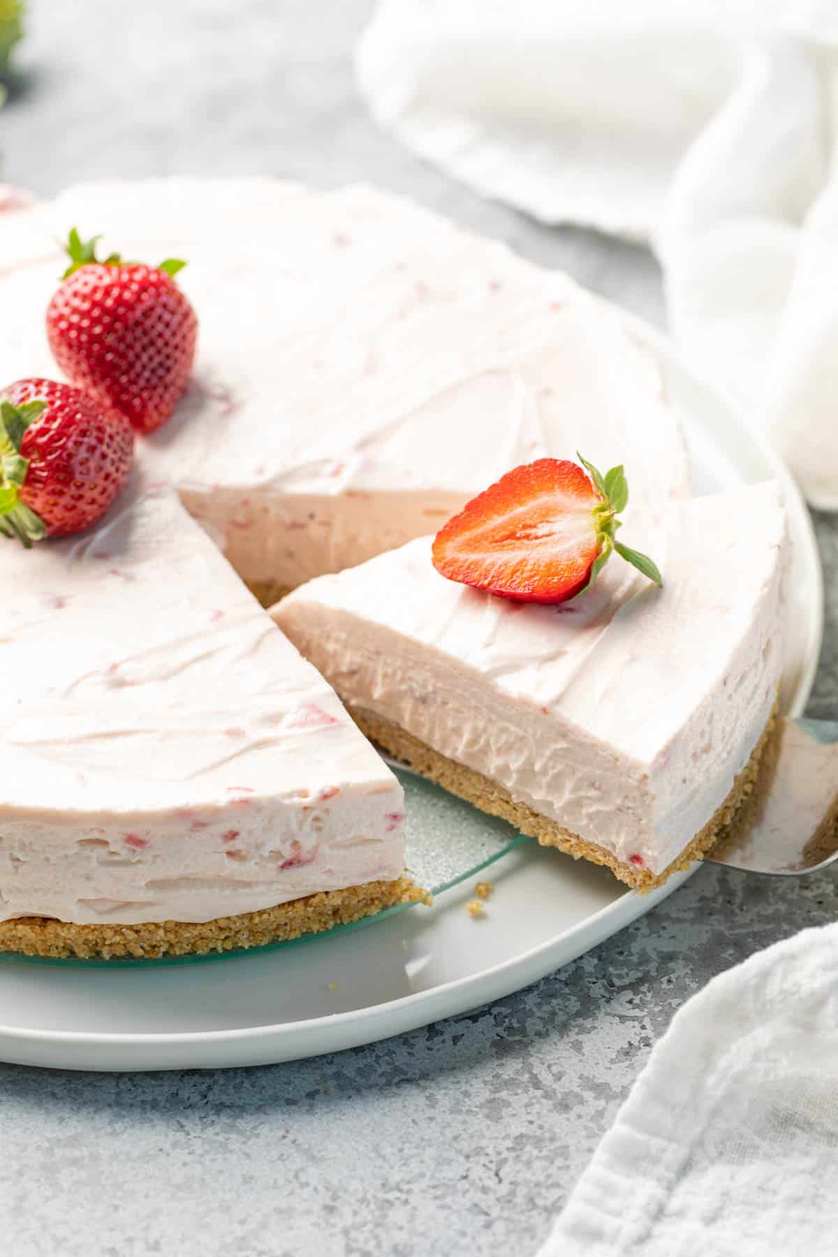 A slice of no bake strawberry cheesecake is removed with a pie server.