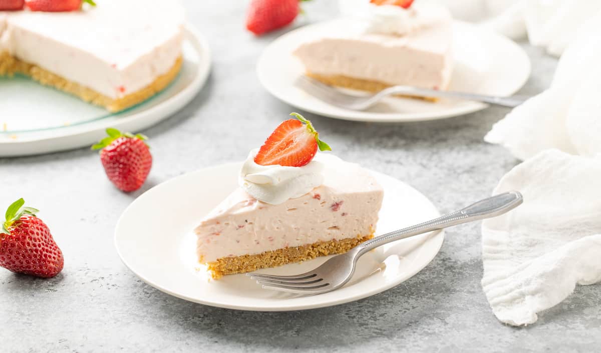 Front view of a slice of no bake strawberry cheesecake on a plate with a fork.
