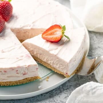 A slice of no bake strawberry cheesecake is being removed with a pie server.
