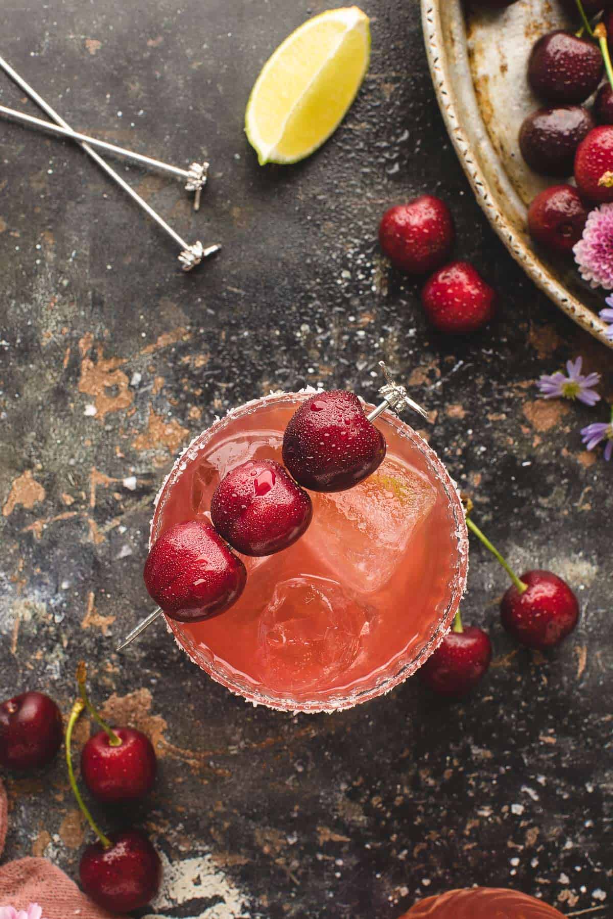 Overhead view of a cherry margarita garnished with fresh cherries.