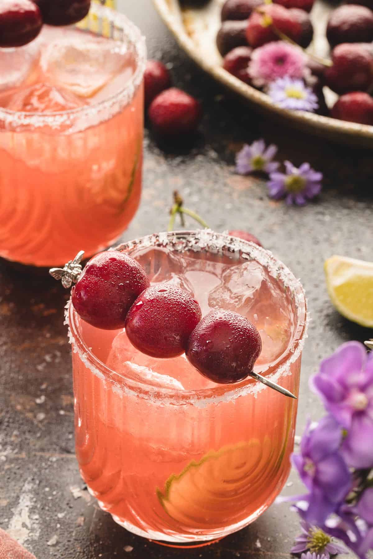 Front view of two cherry margaritas garnished with fresh cherries.