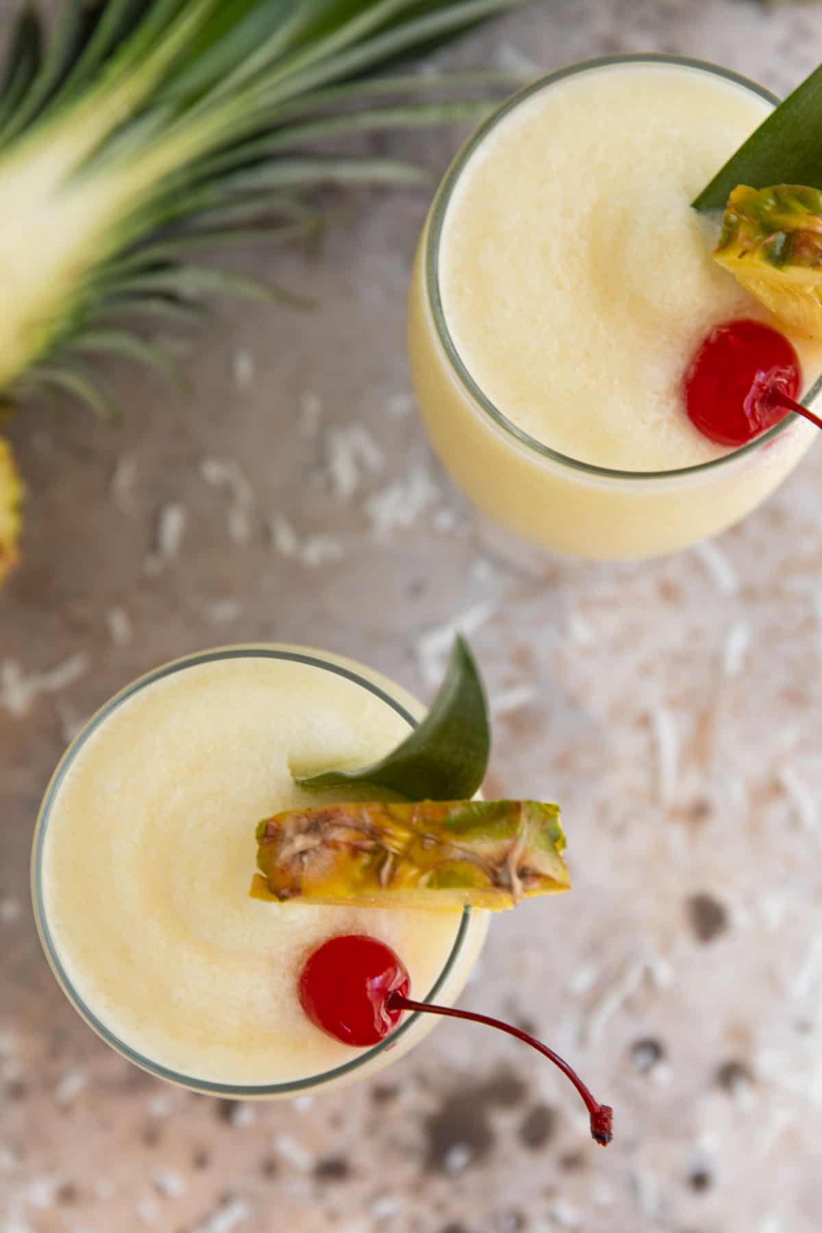 Overhead view of two garnished frozen pina coladas.