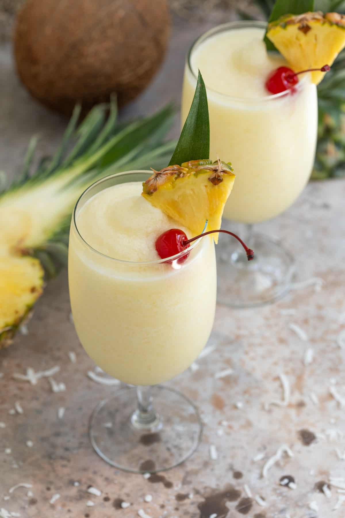 Angled view of two garnished frozen pina coladas.