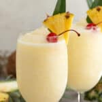 Front view of two garnished pina coladas. Overlay text is at the top of the image.