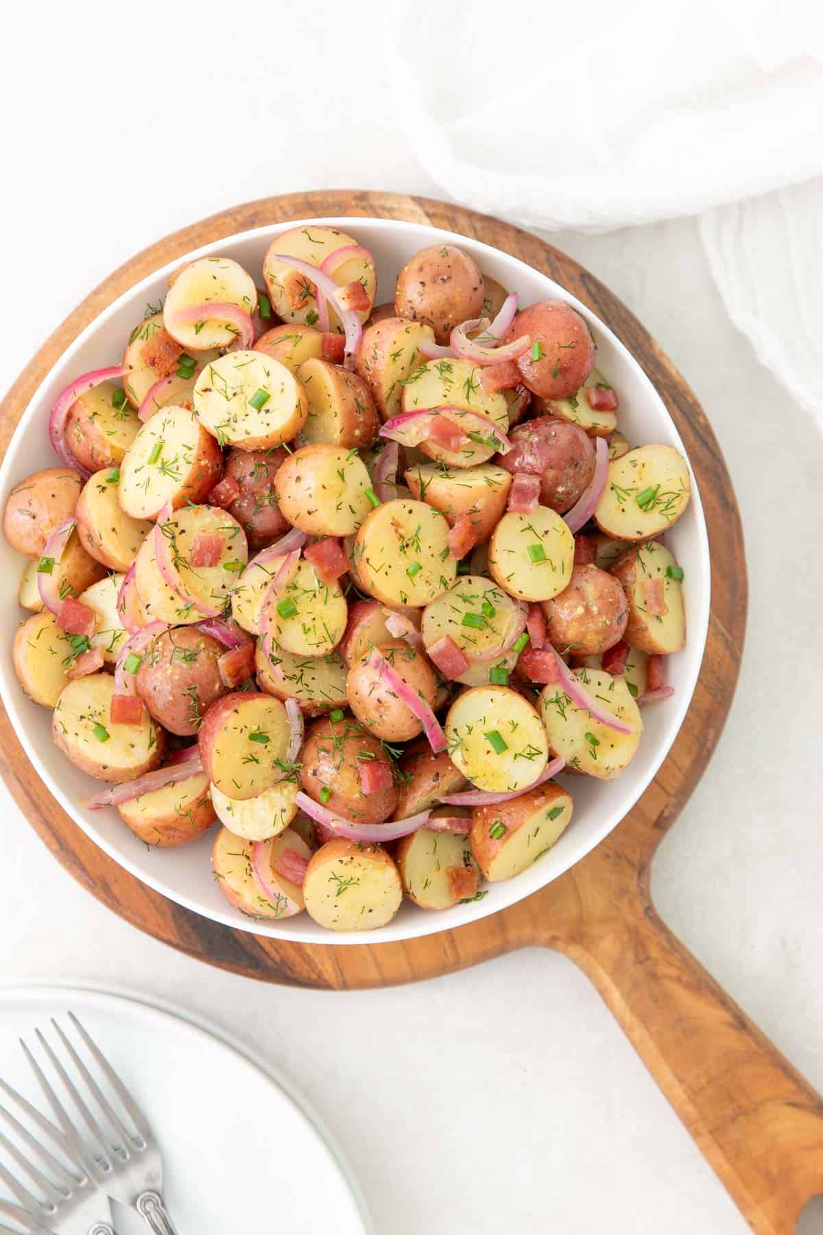 Overhead view of warm potato salad in a white bowl.