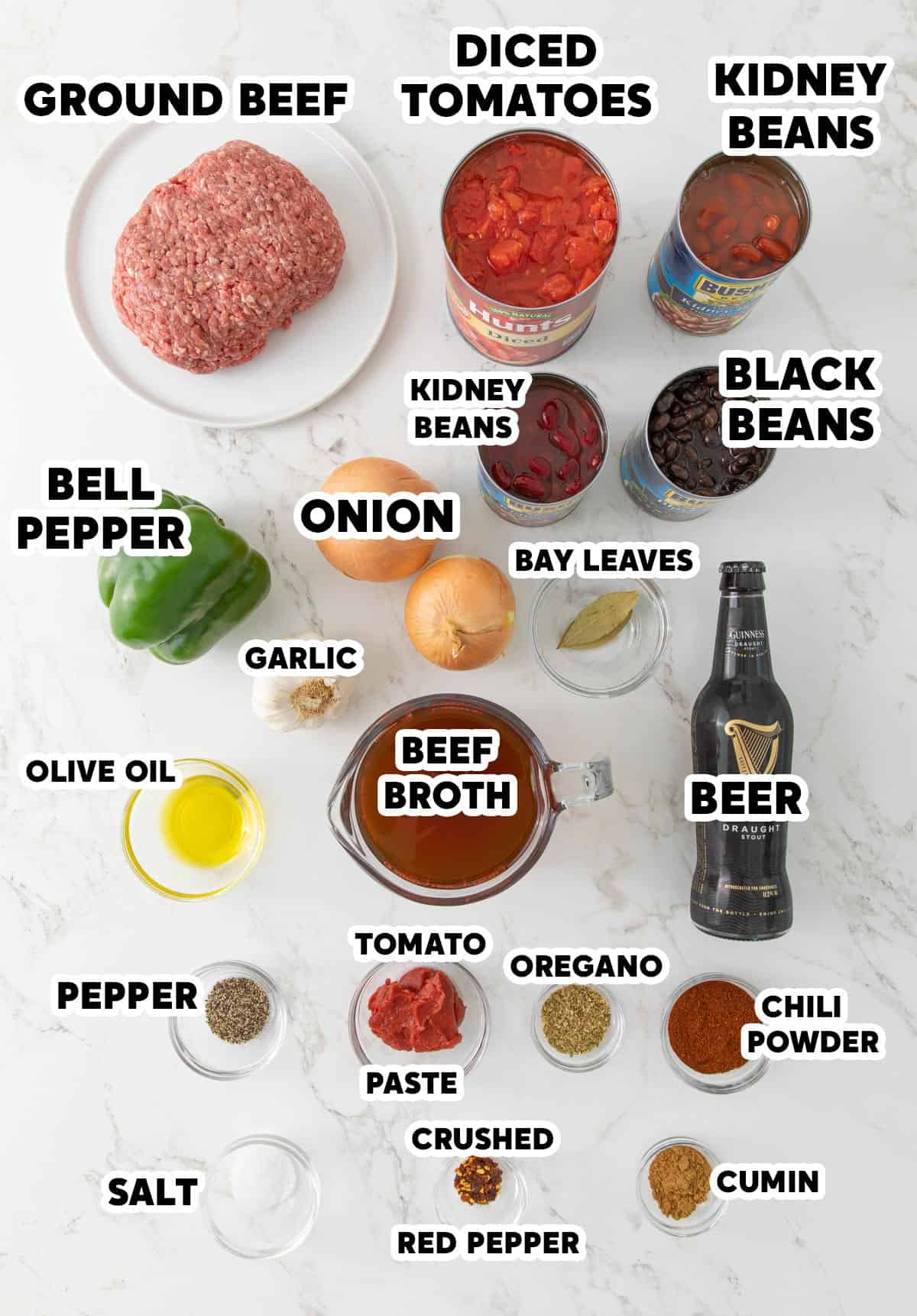 Overhead view of ingredients for making chili with beer on a marble surface.