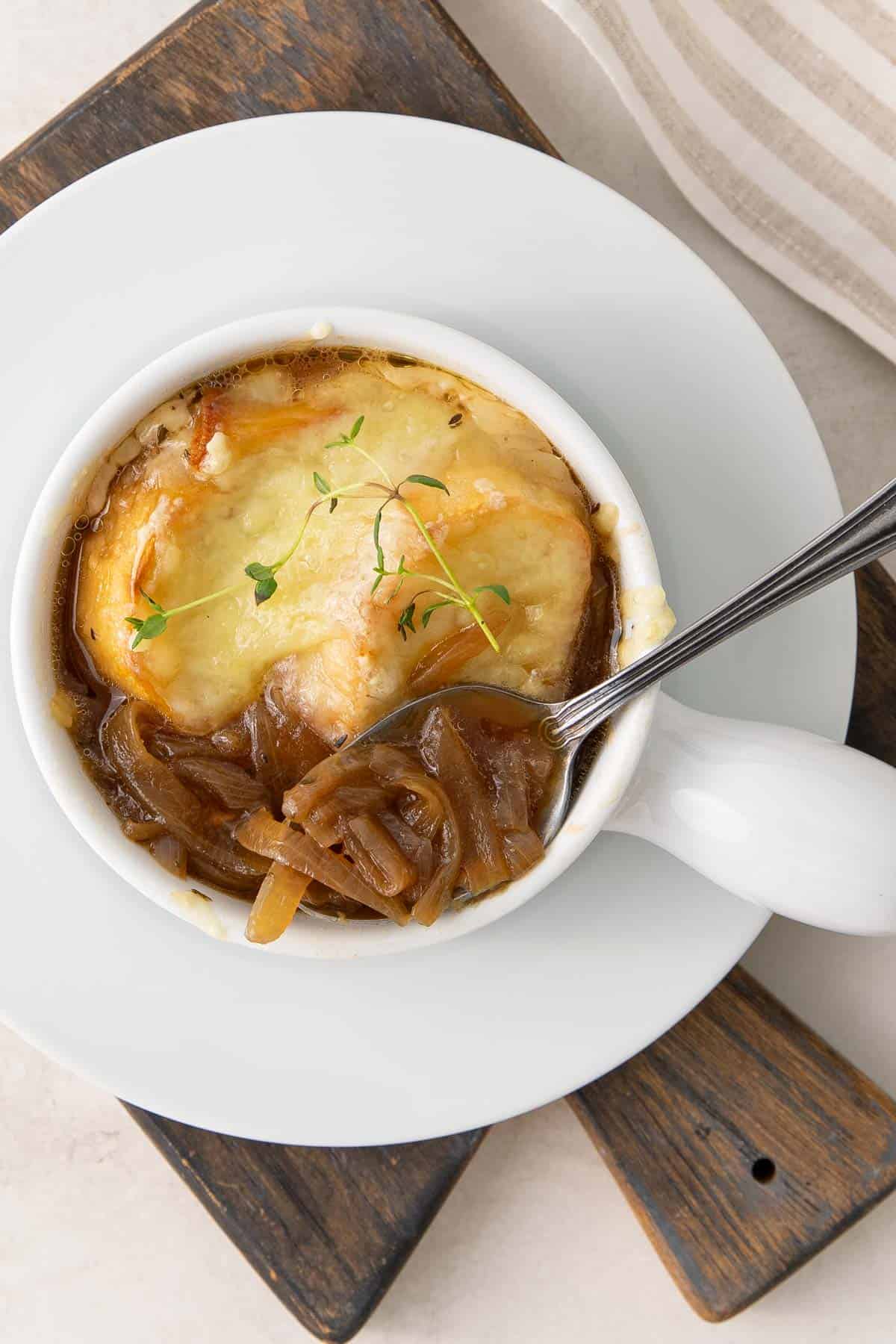 Overhead view of a spoon in a bowl of French onion soup.
