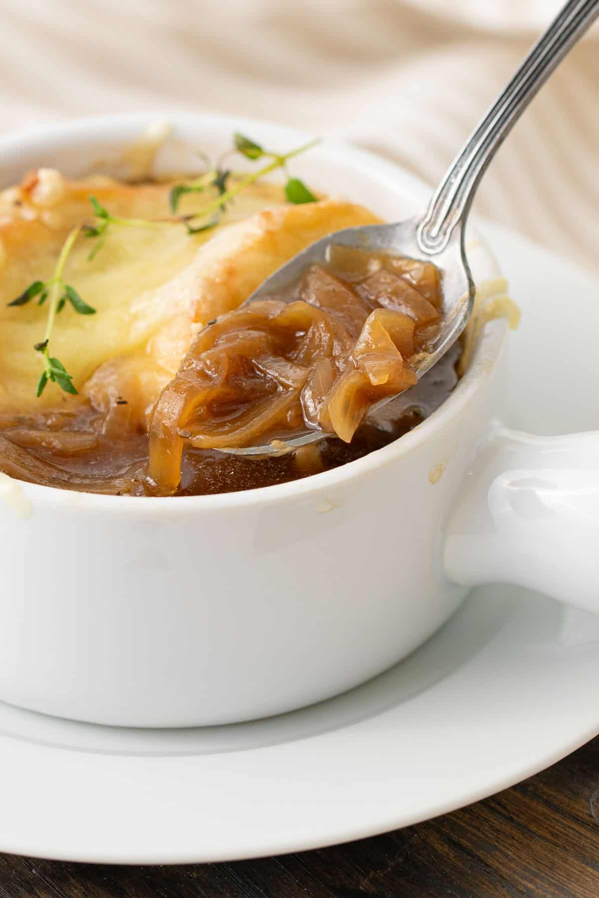 Close up view of a spoon being removed from a bowl of French onion soup.