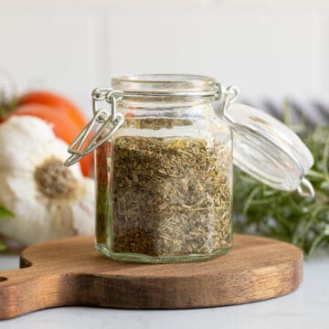 Front view of a glass spice jar filled with homemade Italian seasoning.