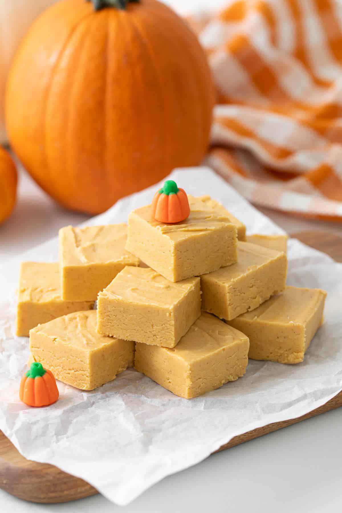 Angled view of stacked pumpkin fudge squares on a piece of parchment paper.