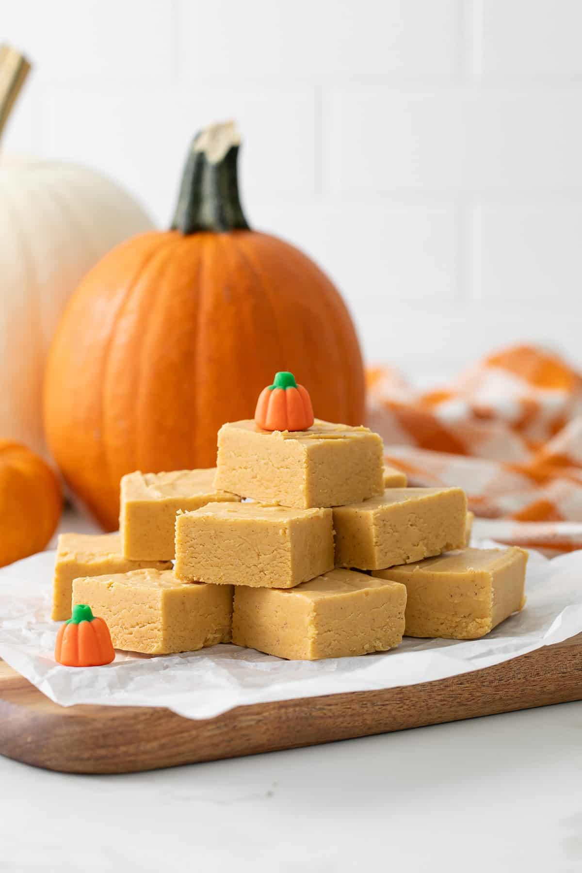 Front view of stacked pumpkin fudge squares on a piece of parchment paper.