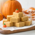 Front close up view of stacked pumpkin fudge squares on a piece of white parchment paper.